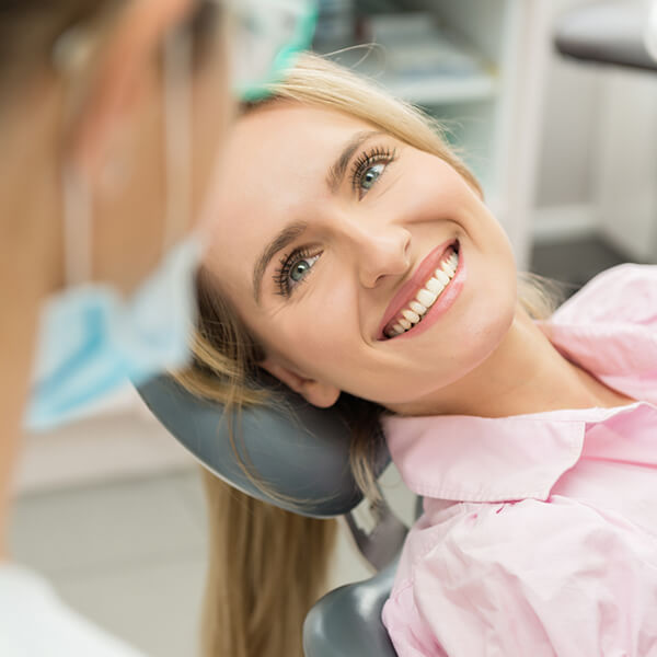 A woman lying in the dentist's chair while smiling